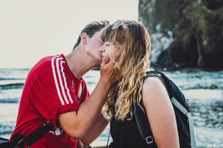 man kissing woman in black top